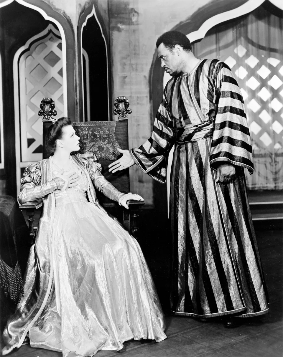 Paul Robeson as Othello standing beside Uta Hagen as Desdemona in a scene from the play.